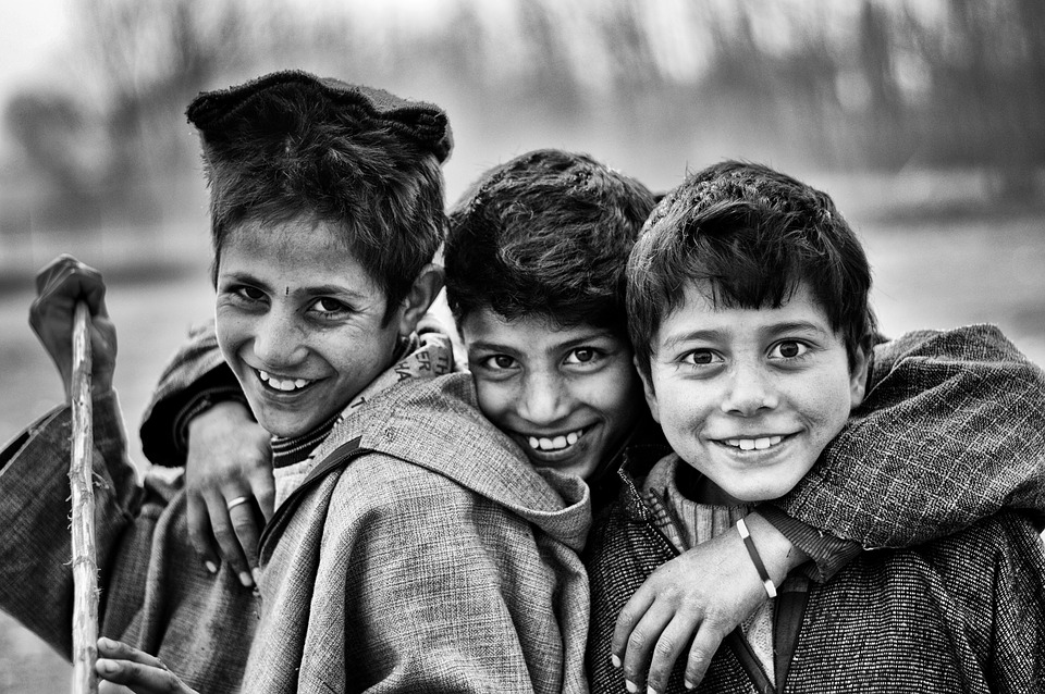 A black-and-white picture of three boys smiling in front of the camera.