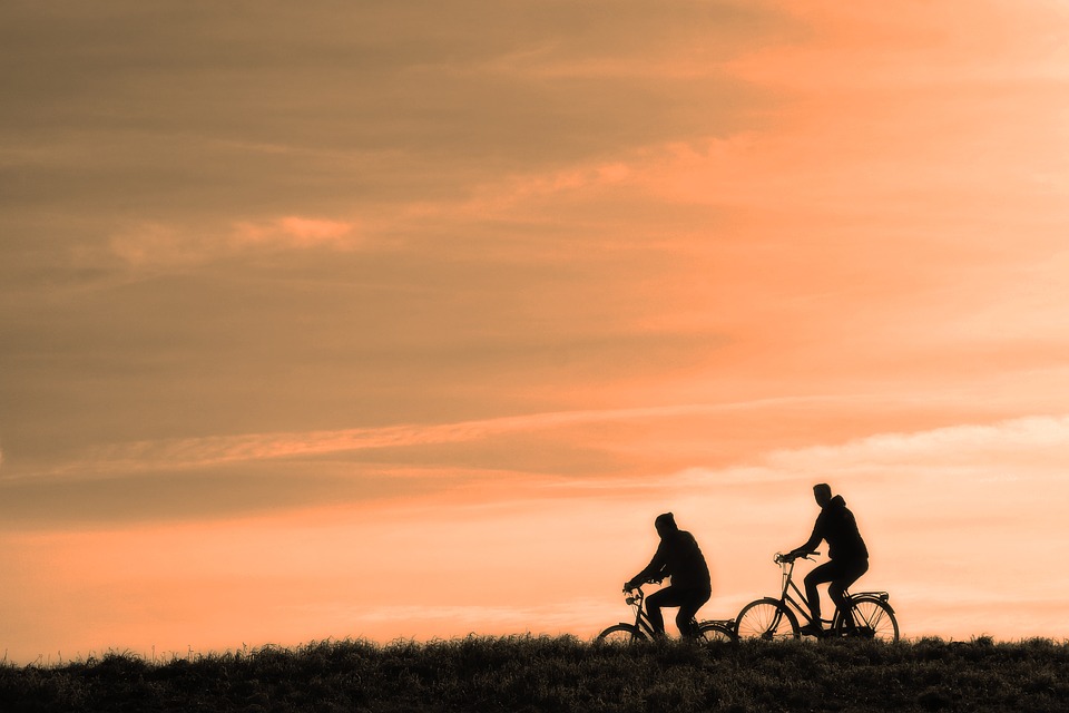 Two people riding bycicles under a sunset.